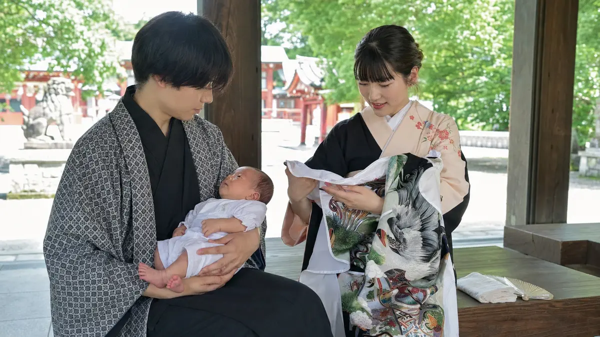 夏のお宮参りで産着を外して休む家族 夏のお宮参りで産着を外し日陰で赤ちゃんを休ませる日本人夫婦